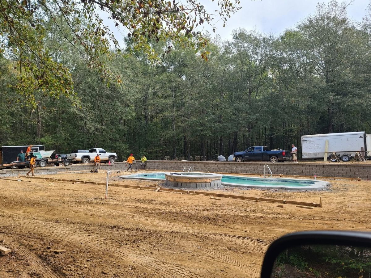 Crew trucks parked beyond a pool where the deck forms are being set